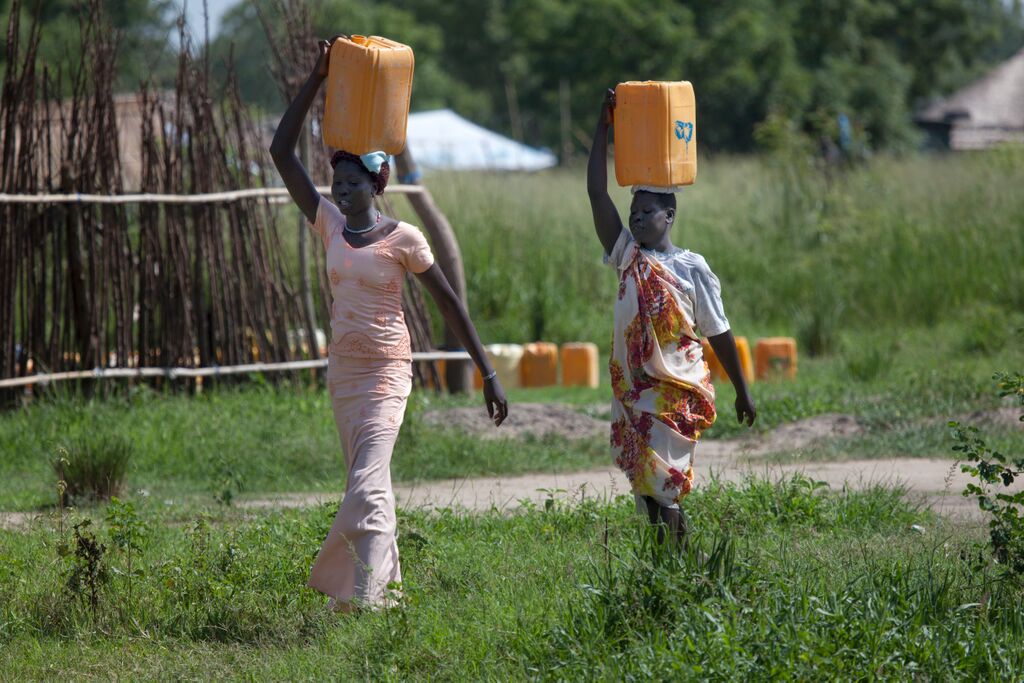 South Sudanese women carrying water on their heads on the fields