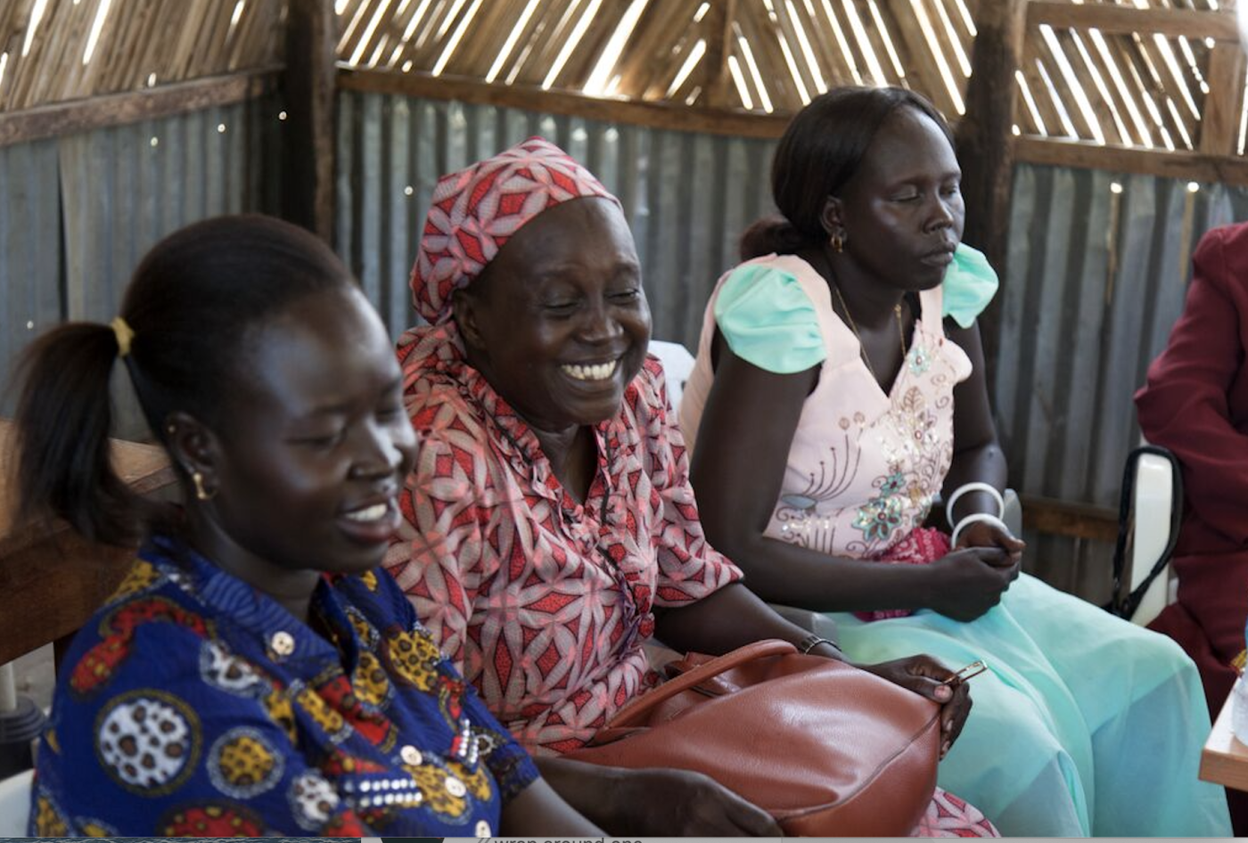 Three south Sudanese women sitting next o each other smiling