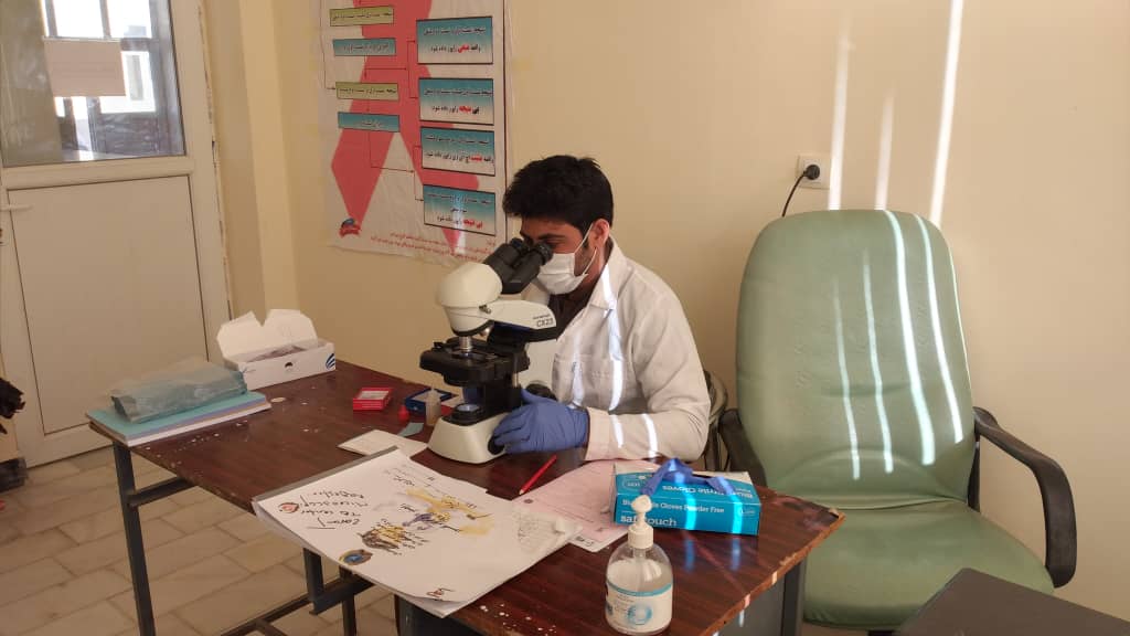 Afghan laboratory technician performing sputum examination in Nimroz