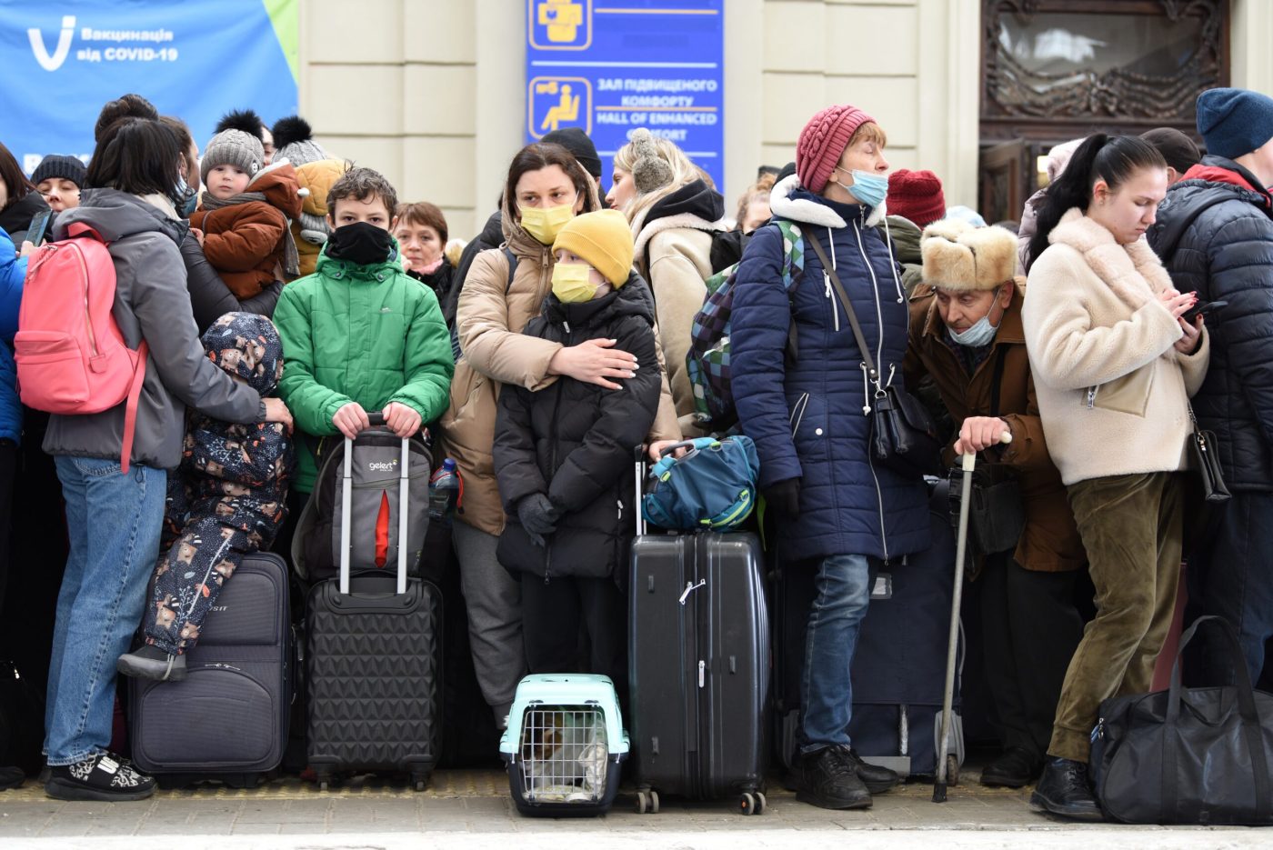 Ukrainian people standing in the railway stating with their bags