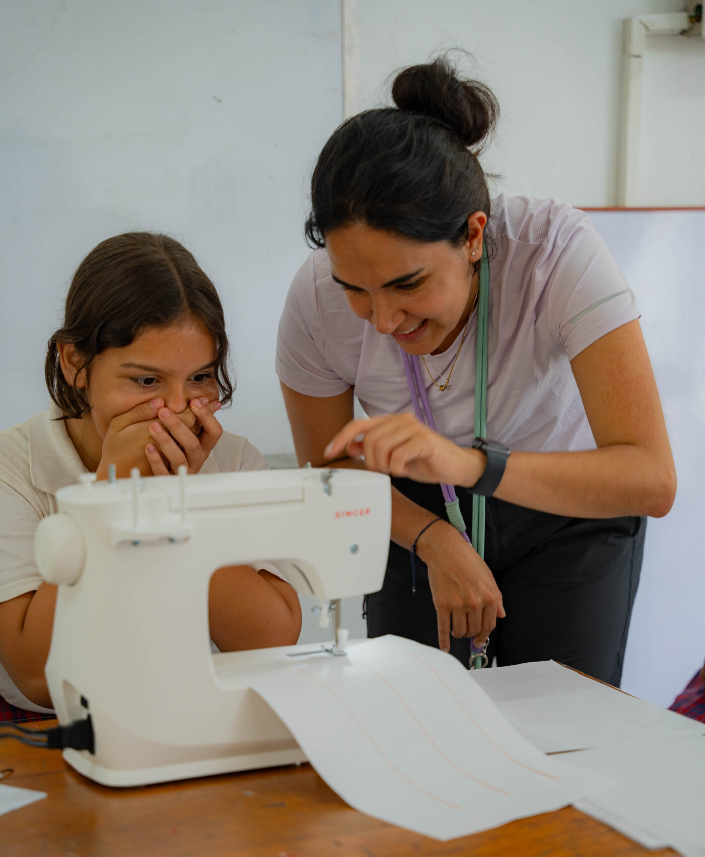 A Colombian young woman is teaching a teenager how to sew