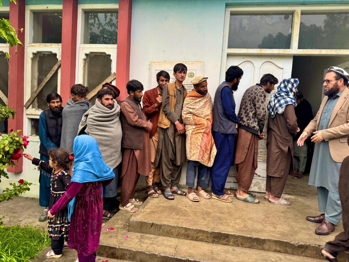 Afghan men in living to receive emergency aid after flooding in Kunar