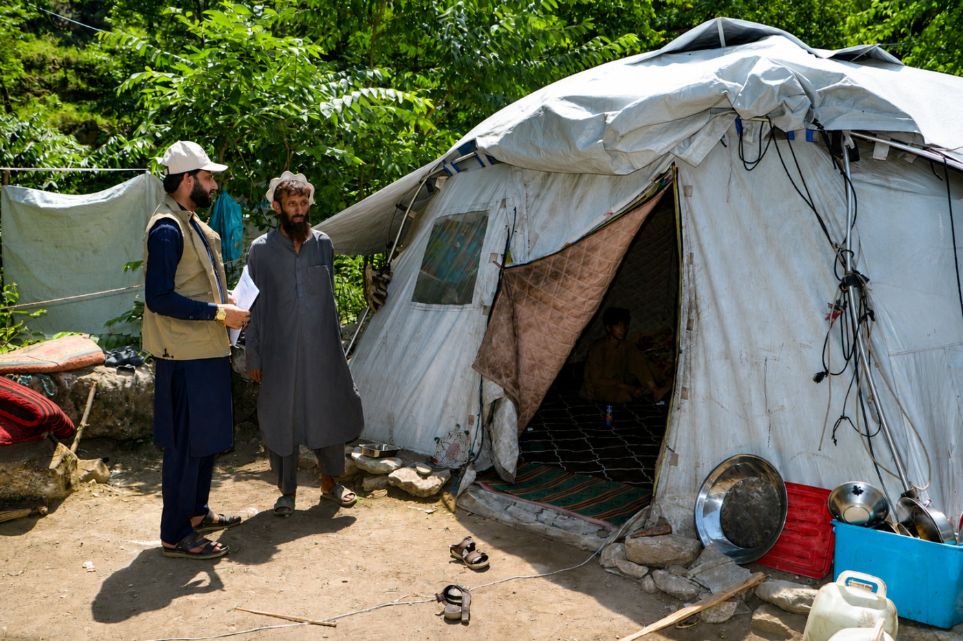 A HealthNet TPO staff member speaks with a community member outside a temporary shelter in Arrit Valley, Kunar, Afghanistan.